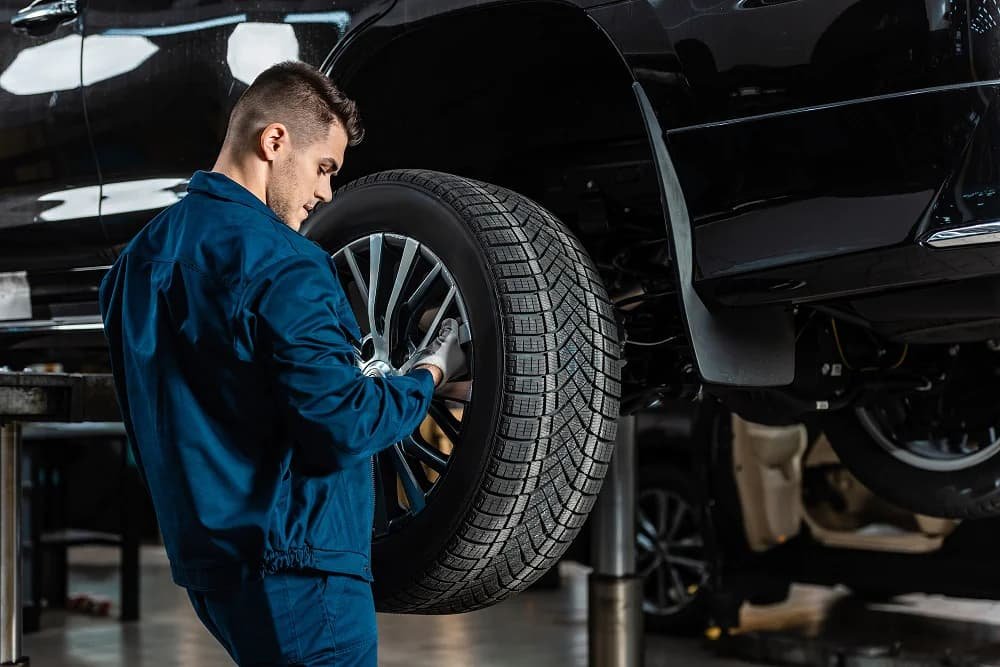 Close-up image of a mechanic using a calibrated torque wrench to tighten forged wheel lug nuts in a star pattern inside a clean automotive workshop, illustrating correct wheel installation and torque procedure to ensure safety and prevent hub stress.