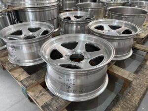 Angled view of a FLEXIFORGED deep-dish 5-spoke forged wheel prototype, highlighting the concave spoke depth and stepped lip in unfinished machined aluminum
