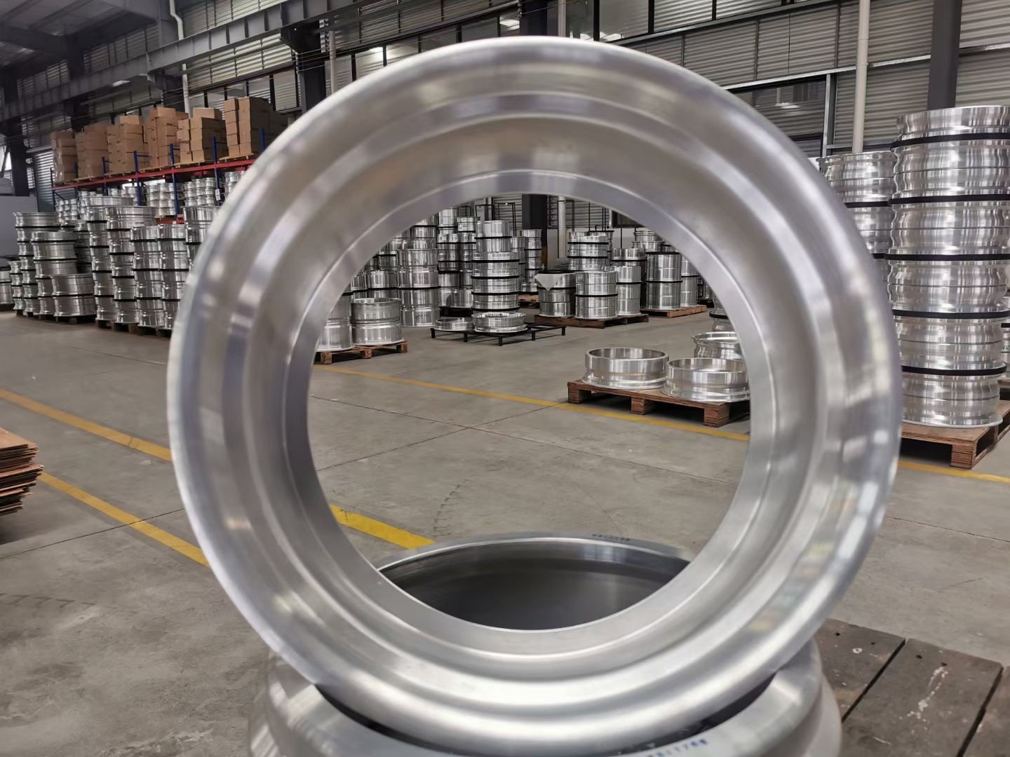 Spun aluminium wheel lips and barrels stacked in the warehouse, with a finished barrel in the foreground